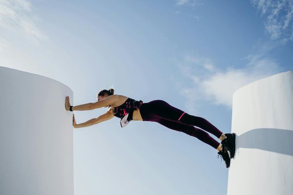 Man performing a controlled bodyweight exercise in a minimalist dark room.